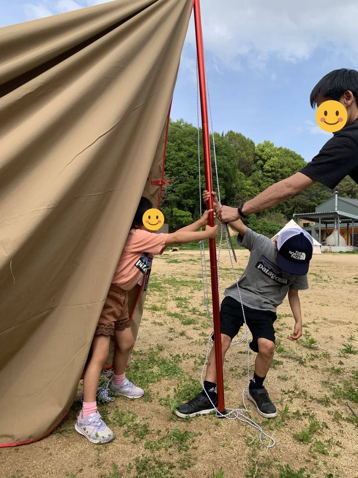 子供たちと一緒にタープのポールを立てているところ