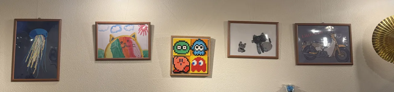 リビングの壁に並ぶ子供の作品たち。Procreateで描いたクラゲの絵、図画工作の絵、レゴやアイロンビーズの作品